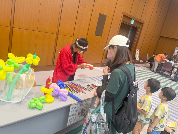 ステージイベント「バルーンアート」に並ぶ親子の様子