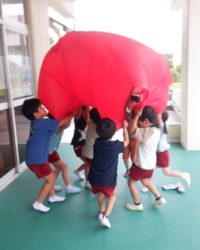 5歳児が友達と一緒に布を使ってバルーンをして遊んでいるところ