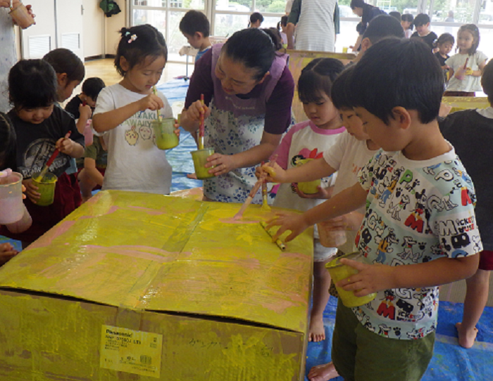 3歳児と4歳児が段ボールにえのぐをぬっているところ