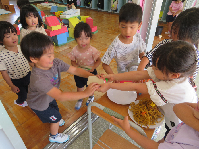 女の子が男の子に紙で作ったハンバーガーを渡している所