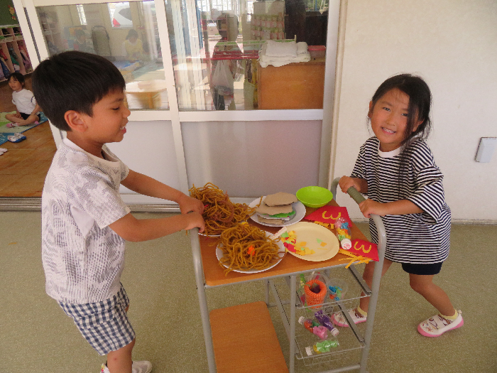男の子と女の子がワゴンにのっているご馳走を運んでいる