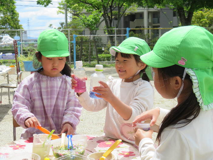 4歳児3人の女の子が色水を作っている姿