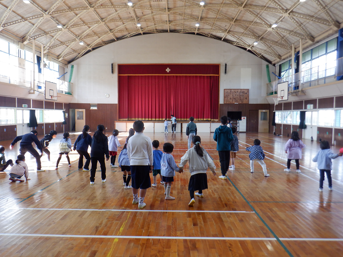 小学5年生と一緒に体育館でだるまさんがころんだをしている5歳児