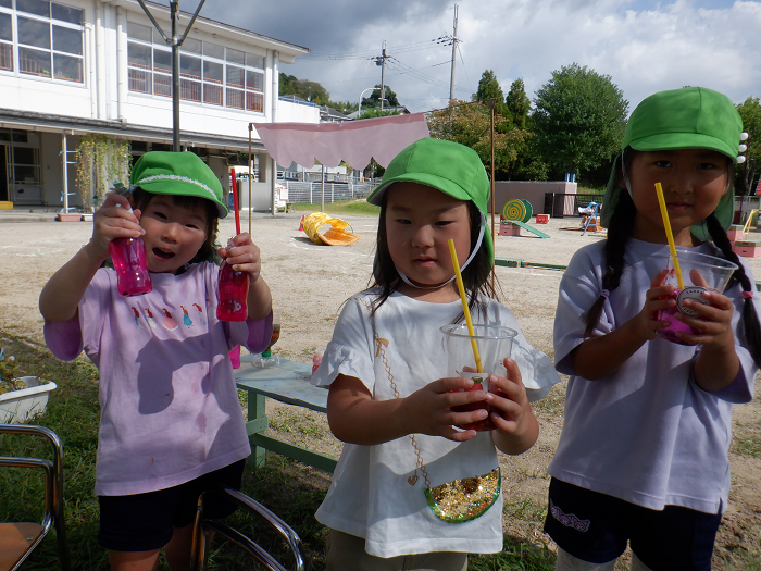 お花で色水を作った容器をもつ子どもの様子