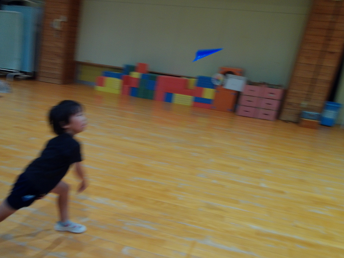 4歳児が、遊戯室で紙飛行機をとばしている