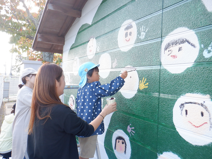 おうちの方と壁に絵をかいている5歳児