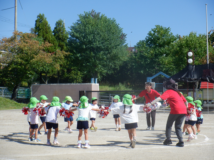 先生や友達とみんなで輪になって手をつないで踊っている様子