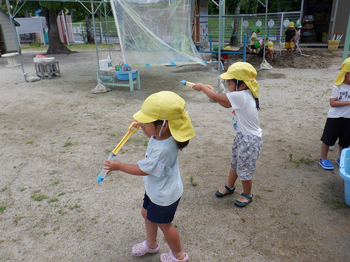 的に向かって水鉄砲を打っている4歳児二人