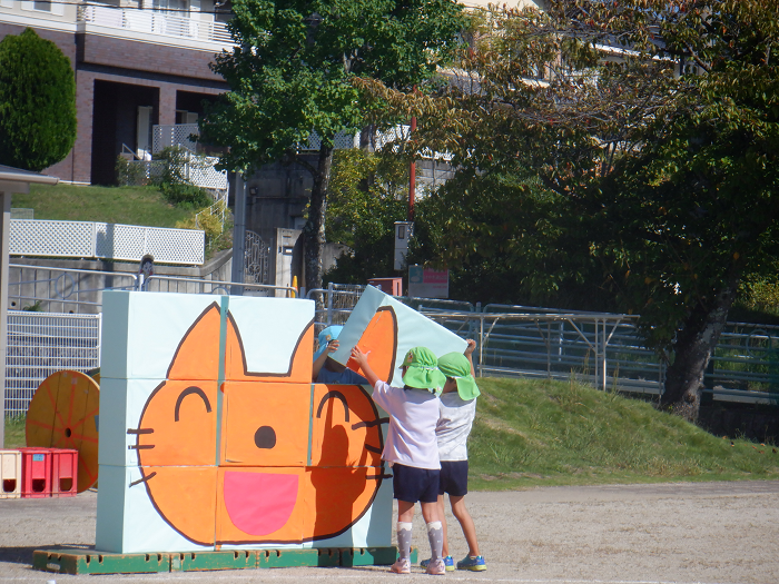 段ボールで作った猫の大きなパズルを友達と一緒に組み立てている様子