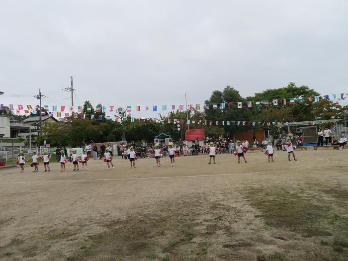 4歳児が手にポンポンをつけてみんなで踊っている様子