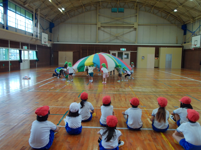 5歳児がバルーン遊びをしているところを小学生が見ている