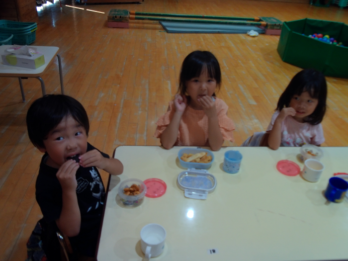 3人の子どもが椅子に座っておやつを食べている