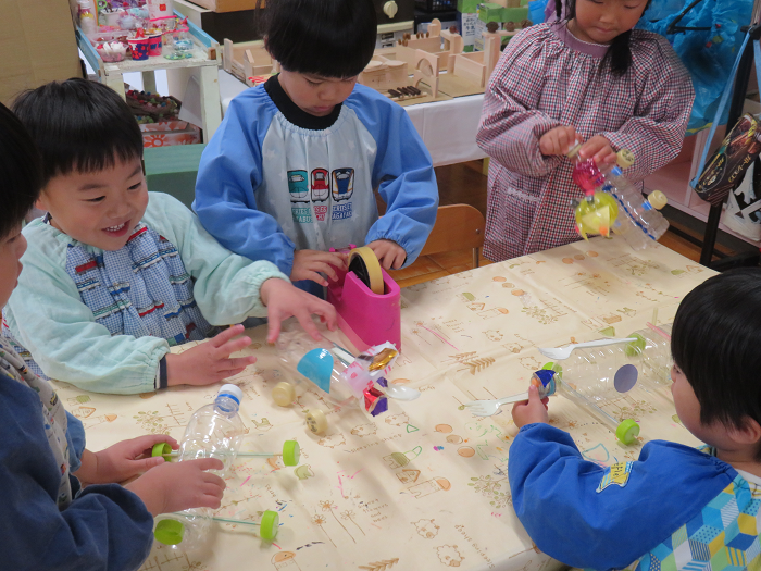 4歳児が5人集まり、ペットボトルを使って車を作っている