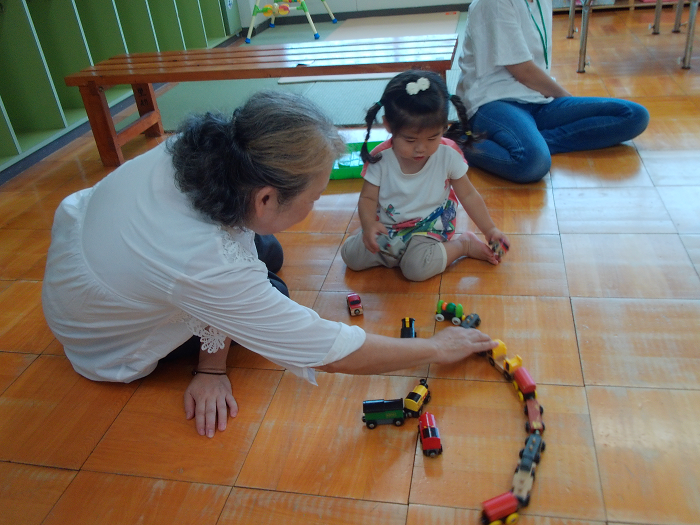 子育てサポーターの方と2歳児が電車で遊んでいる
