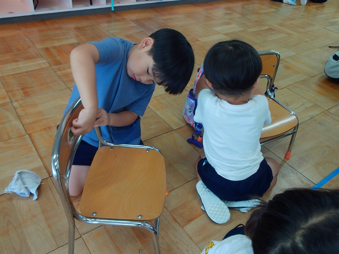 自分の椅子についたテープをはがしている3歳児二人
