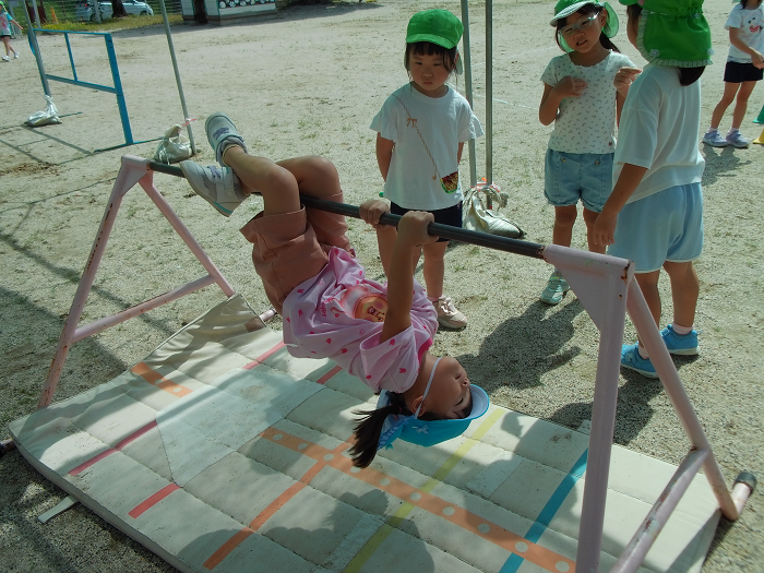 3歳児が、鉄棒に手足をひっかけてぶら下がっている