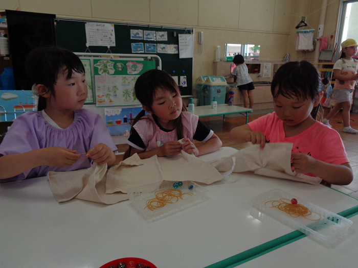染め物をするためにランチョンマットを輪ゴムで結び模様をつける子どもの姿