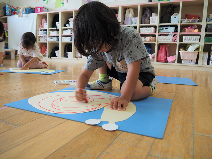 かたつむりのお絵描きをする3歳児