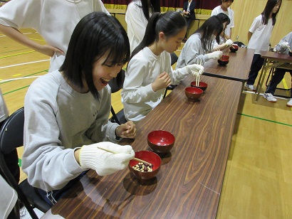 軍手をはめて豆つかみを体験する生徒