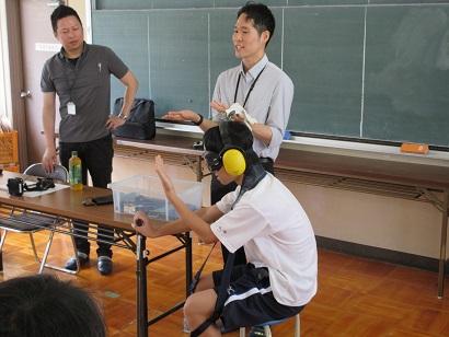 高齢者疑似体験グッズの取付方法を説明する職員