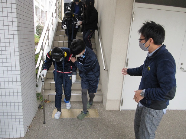 高齢者疑似体験セットを装着し階段を下りる様子