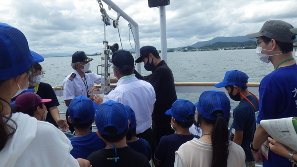 琵琶湖でバンドーン採水器を引き上げる様子を見守る団員たち