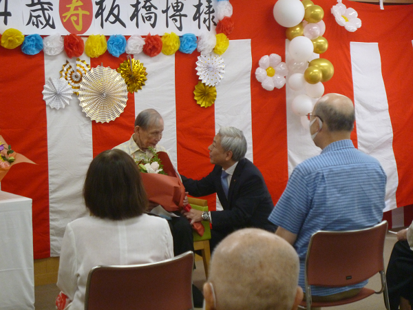 大津市内男性最高齢者の板橋さんへ、市長から花束を贈呈する様子