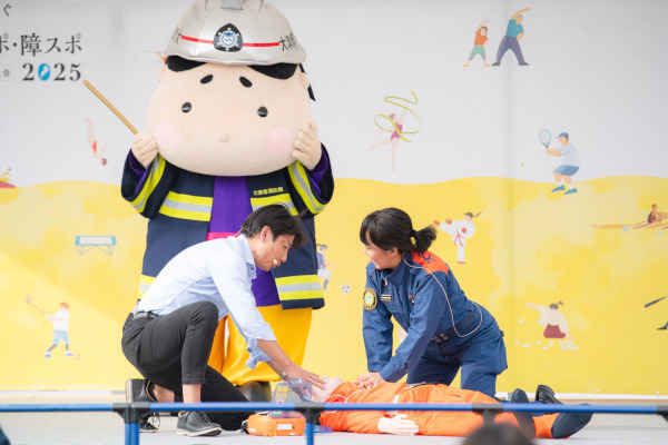 「AED GO」 普及PRのためにAEDの使用方法を説明する様子