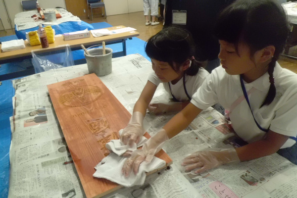 工作体験　東海道統一案内看板のベンガラを拭き取る様子