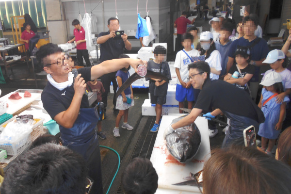 マグロの尾をカットして断面を参加者に見せる様子