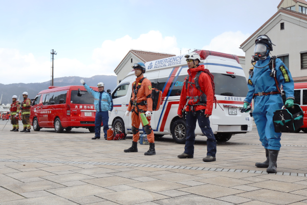 消防車両装備披露、消防車、救急車の前でさまざまな服装で整列する隊員の様子