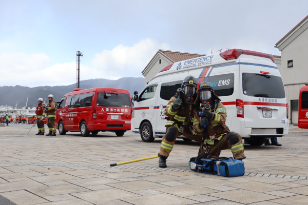 消防車両装備披露、防火服を着用して放水姿勢をとる隊員の様子