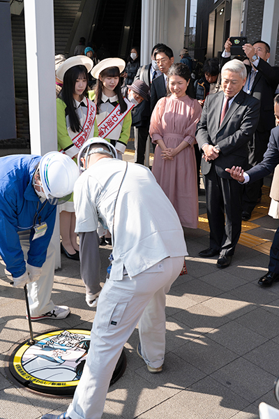 マンホールが京阪膳所駅前に設置される様子を見守る宮島さんと佐藤市長（写真）
