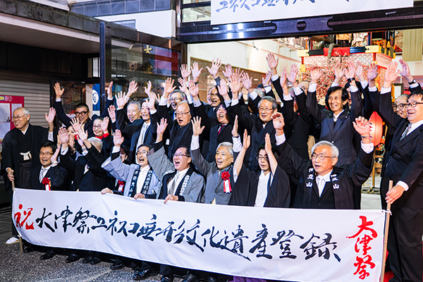 登録決定の記念セレモニーで万歳する関係者と佐藤市長ら（写真）