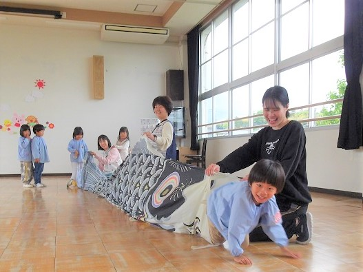 こどもの日のつどいで子どもたちがこいのぼりをくぐる様子