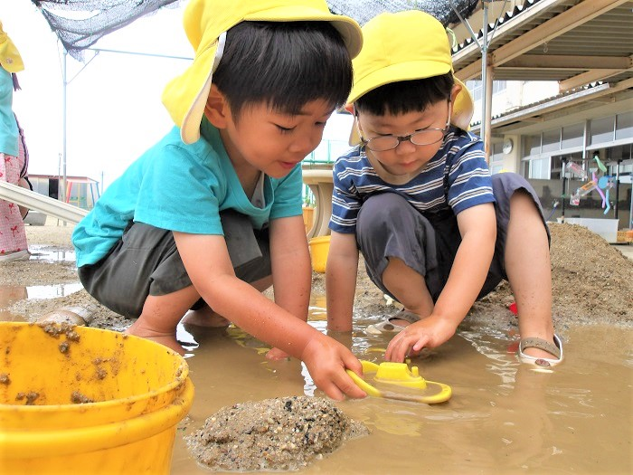 泥遊びをする3歳児