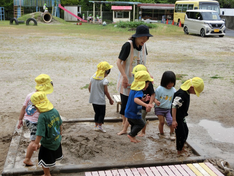 3歳児が砂場で裸足で遊んでいる