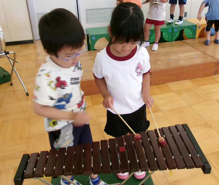 5歳児が4歳児に木琴の演奏の仕方を教えてあげているところ