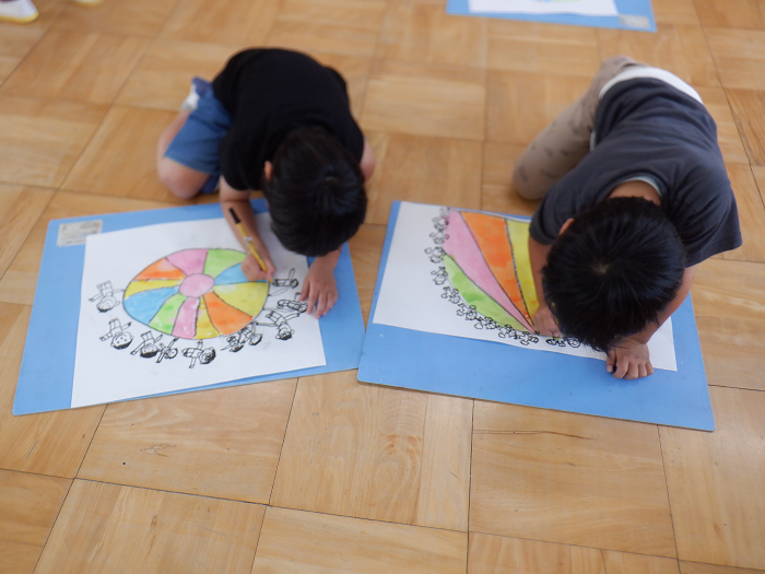 5歳児がサインペンを使ってバルーンや人の絵を集中して描いているところ