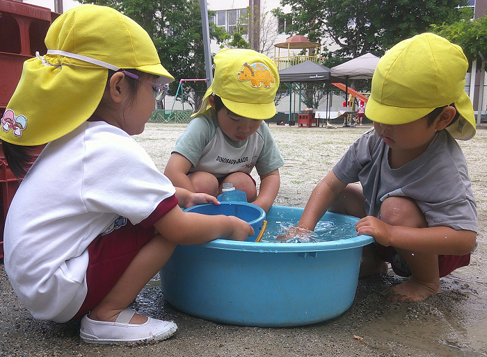 3歳児が砂場の道具を水で洗っているところ