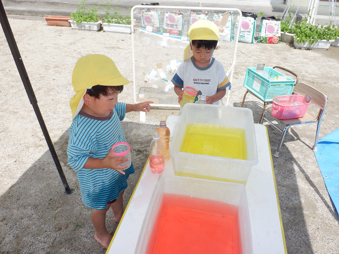 3歳児が色水をペットボトルに入れて遊んでいるところ