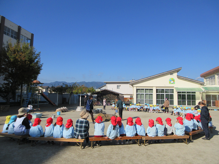 幼稚園児が園庭でやきいもの様子を見ているところ