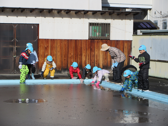 5歳児がプールの水が凍った様子を見ているところ。