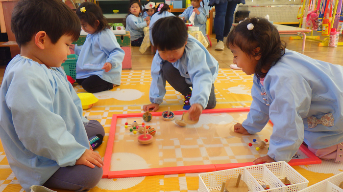 3歳児が友達と一緒にこま回しをして遊んでいるところ。