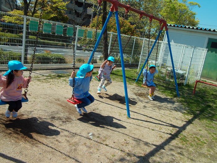 3歳児四人がブランコに乗っている
