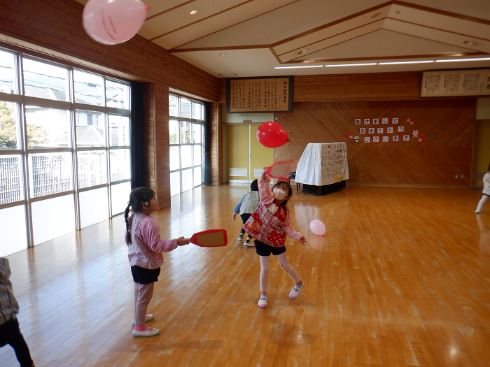 女児二人が室内で、風船を使った羽根つき遊びをしている