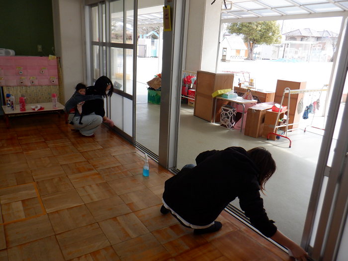 保護者が保育室の窓のレールを拭き掃除している