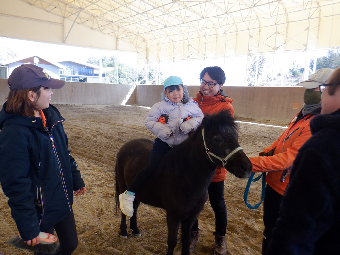 職員に支えられ馬のポニーに乗っている5歳児