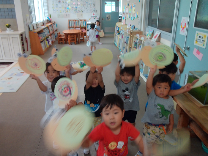 画用紙で作ったカタツムリをもってお散歩をさせている3歳児