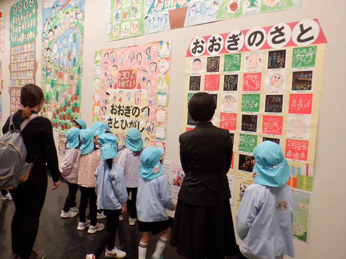 壁に貼った自分たちの絵を先生や友達と一緒に見ている様子